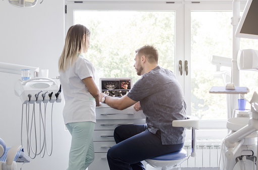 dental staff in office in front of monitors discuss pinhole surgical technique