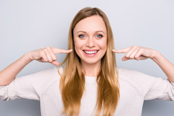 Smiling person pointing at their healthy smile.