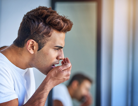 Man testing his breath at Aesthetic Periodontal & Implant Specialists