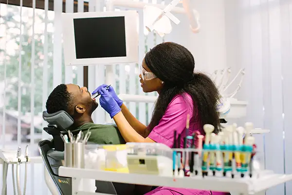 A dentist in a bright clinic examining a male patient's gums due to bleeding.