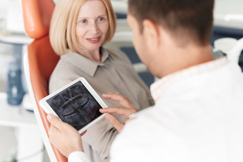 Older woman discussing dental implants with her dentist at Aesthetic Periodontal & Implant Specialists in San Antonio, TX
